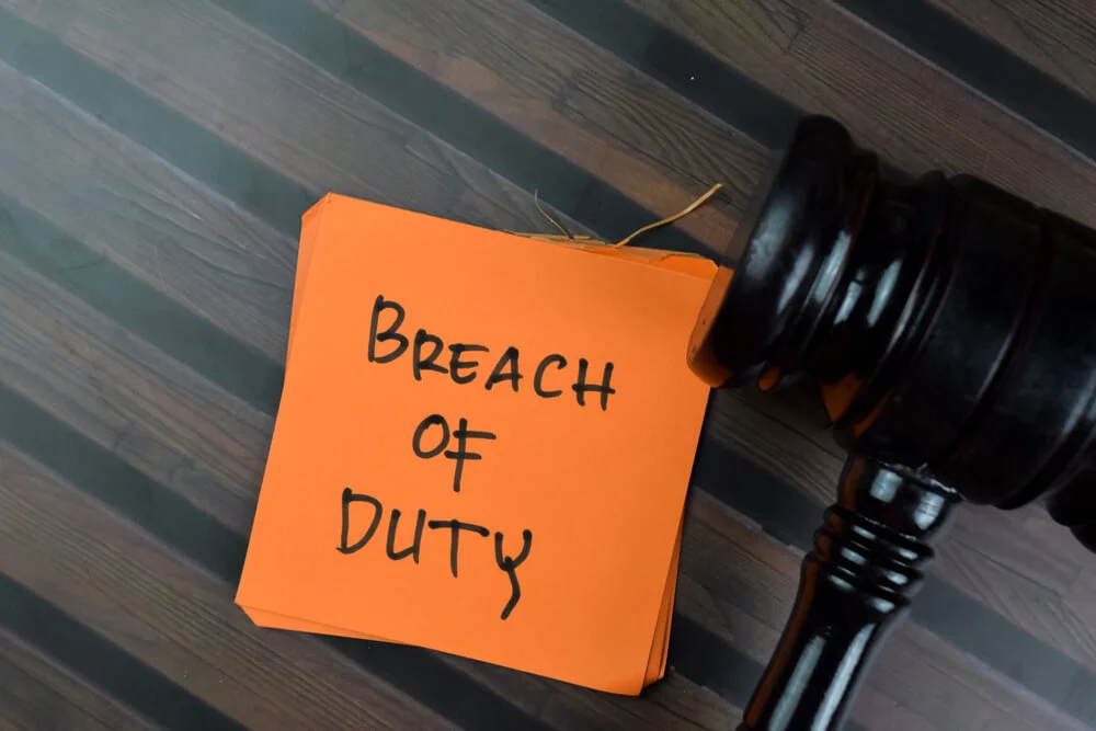 Concept of Breach of Duty write on sticky notes with gavel isolated on Wooden Table.