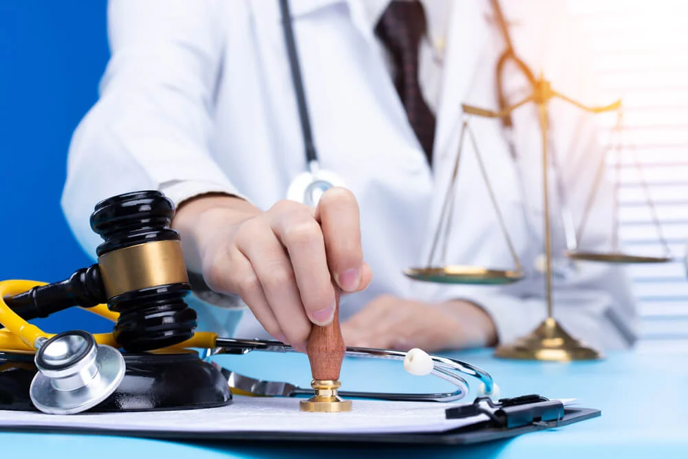 Doctor stamp approval with authority to patient to death. Law legal protect medical doctor from criminal court judgement. Concept with stethoscope balance scale mullet hammer, copy space