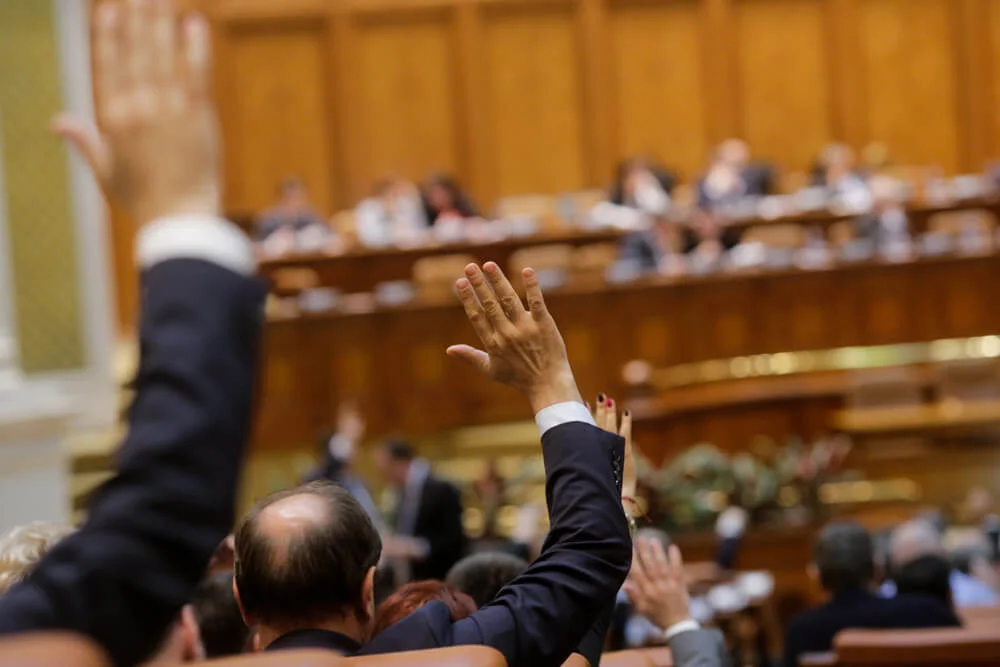 Members of Romanian Parliament vote by raising their hands