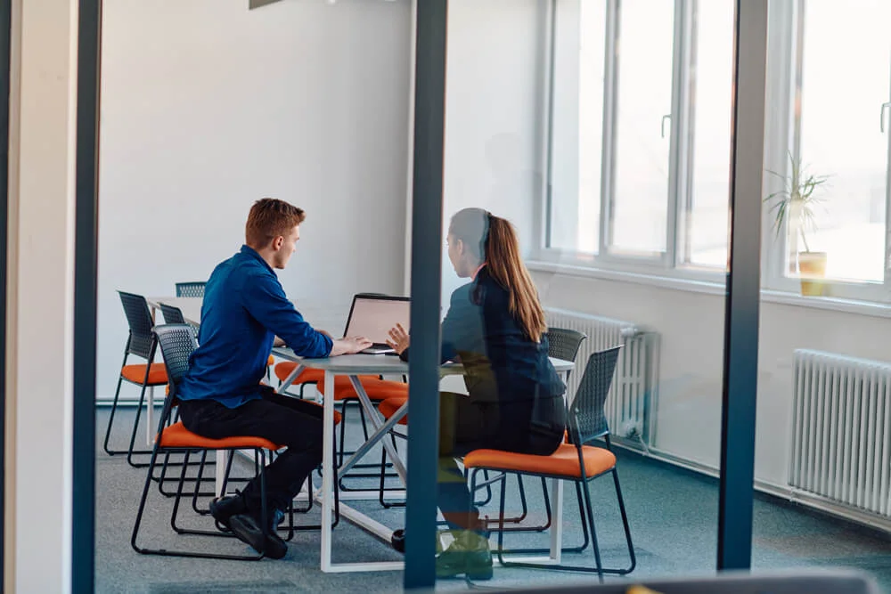 A business leader in a suit conversing with her worker in the IT industry about new business projects and existing business problems