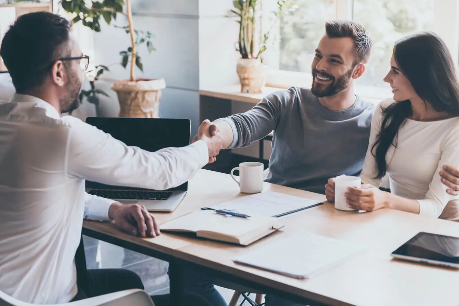 Cheerful young man bonding to his wife while shaking hand to man